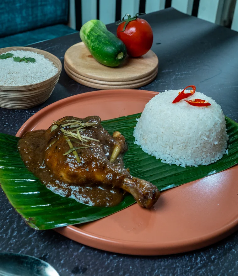 Chicken rendang with steamed rice on banana leaf